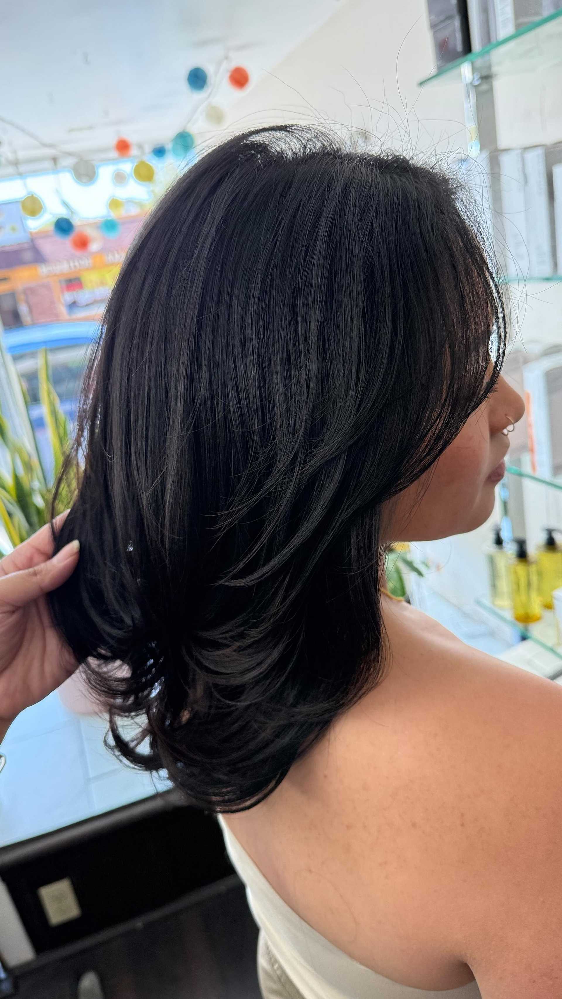 Sleek black hair styled in a salon, surrounded by vibrant decor and products.