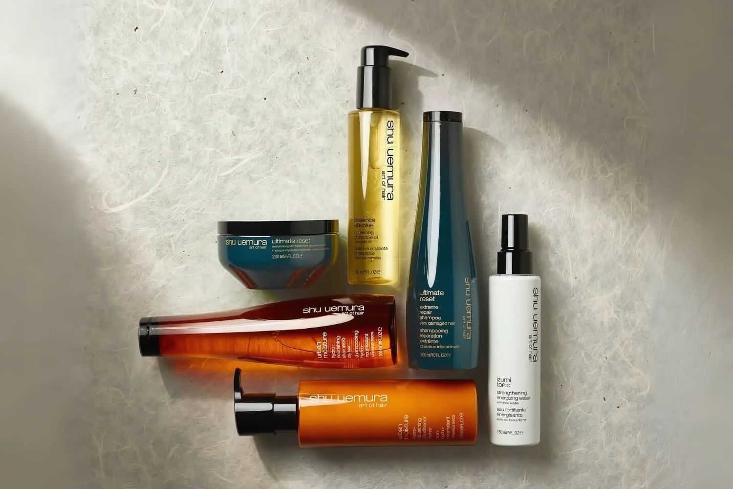 Shu Uemura hair care products arranged on a textured surface.